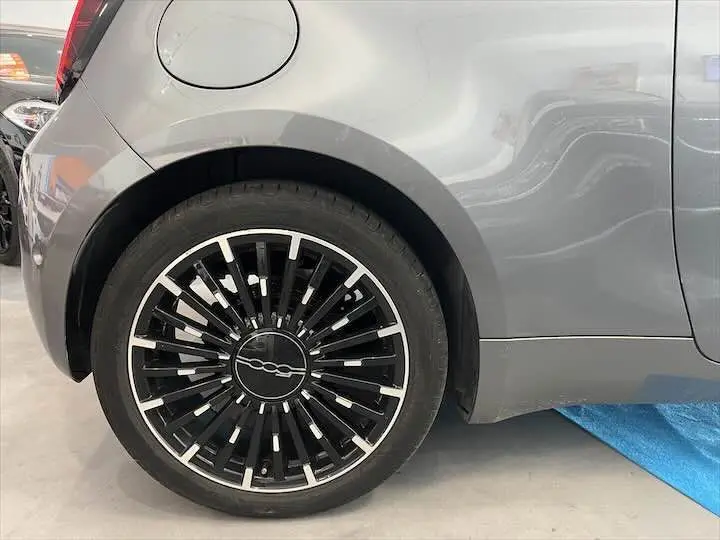 Gros plan sur la roue arrière gauche d'une Fiat 500 électrique gris minéral métal avec jante noire et argentée design moderne.