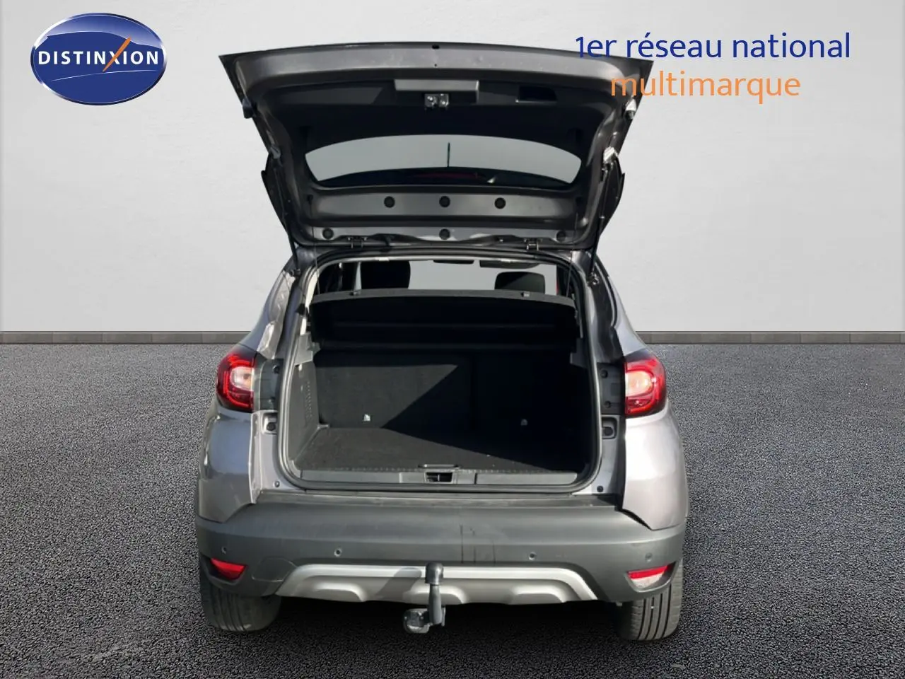Vue arrière d'un Renault Captur gris 2019 avec coffre ouvert et attelage visible sur sol goudronné.