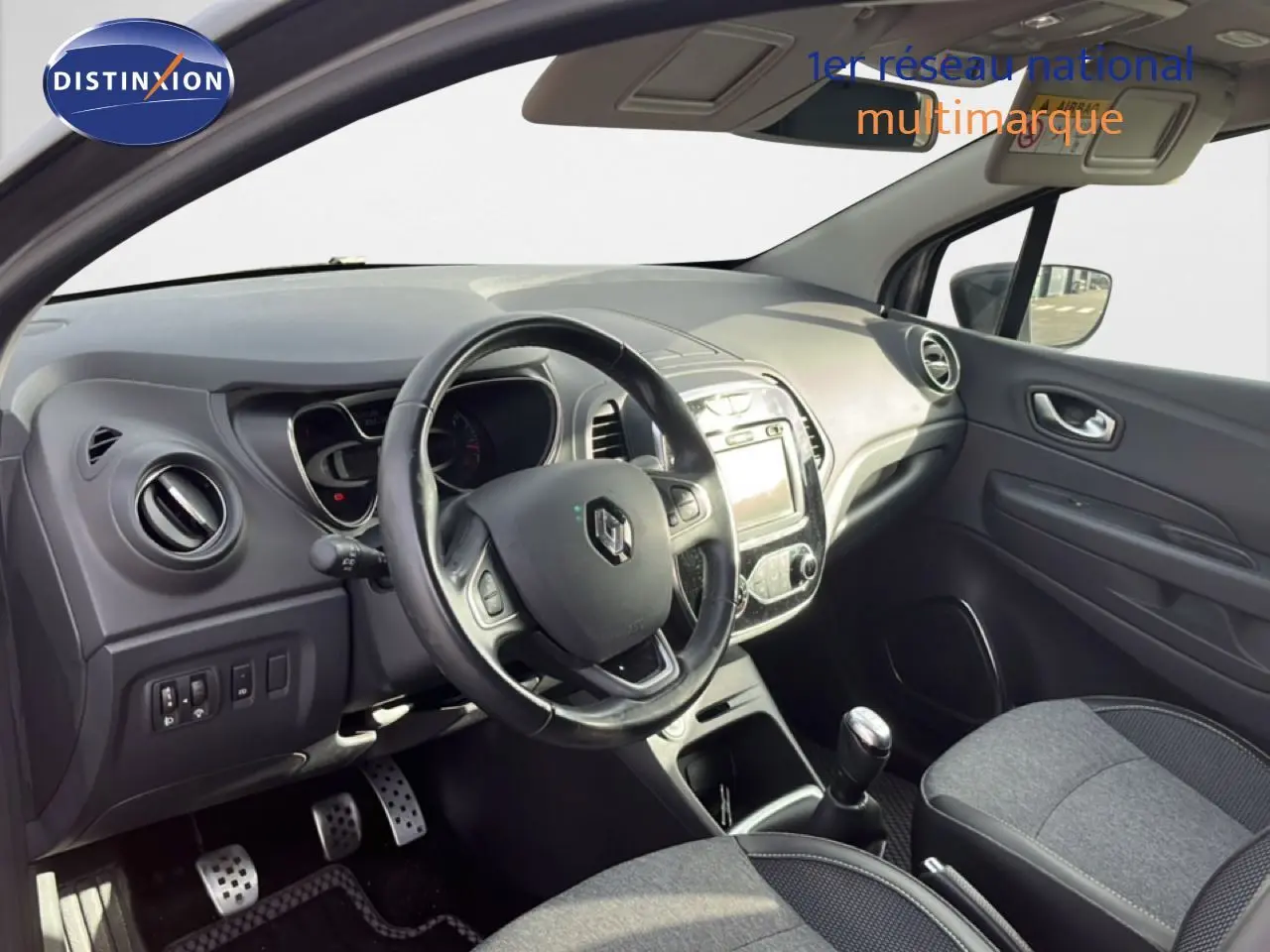 Vue intérieure côté conducteur du Renault Captur gris 2019, montrant le volant, la console centrale et la boîte manuelle.