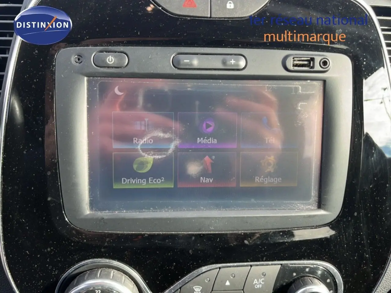 Écran tactile central du tableau de bord du Renault Captur gris, avec commandes multimédia et climatisation visibles.