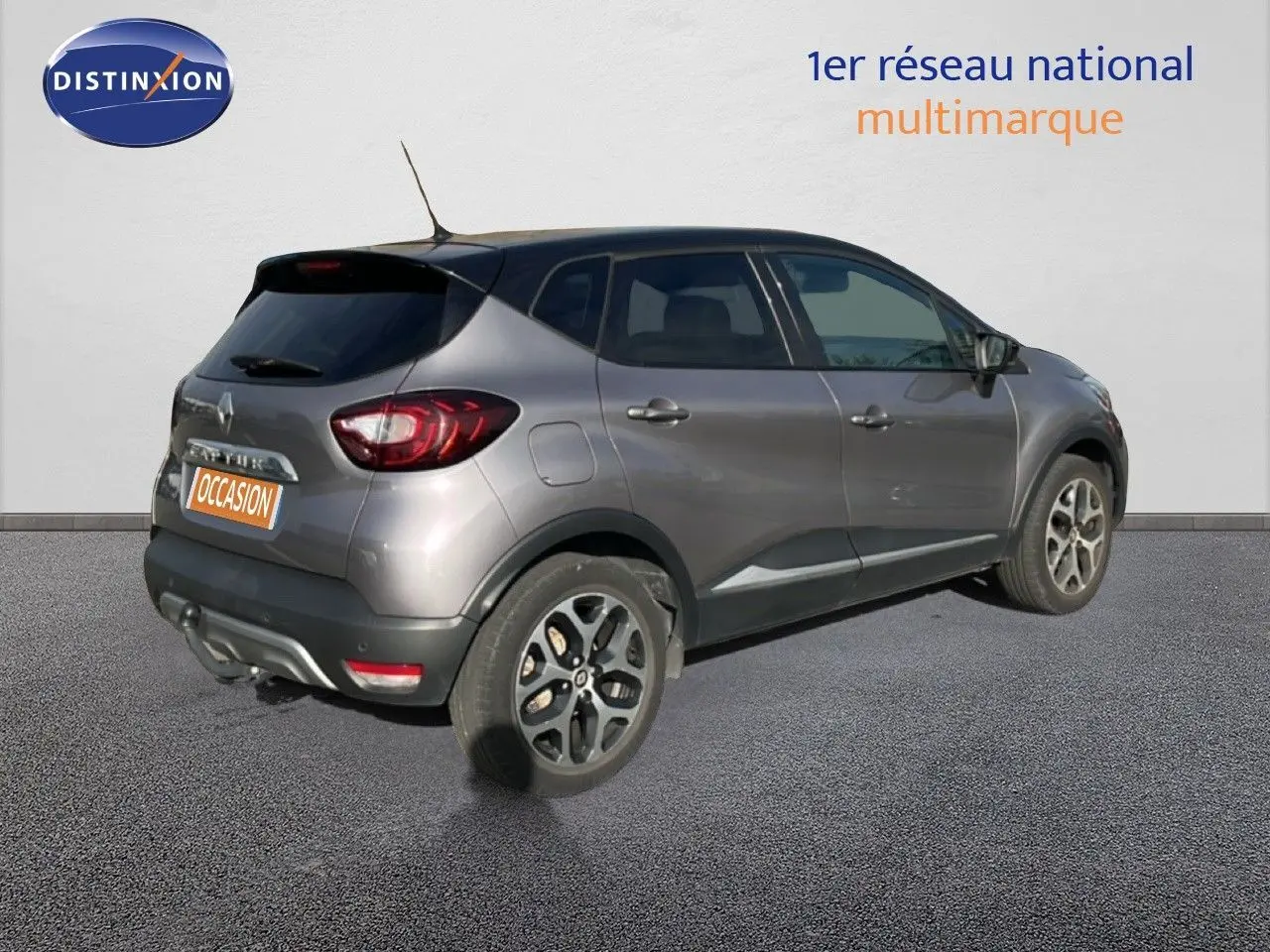 Renault Captur gris vue 3/4 arrière droit, avec jantes alliage et feux arrière distinctifs, stationné sur sol gris.