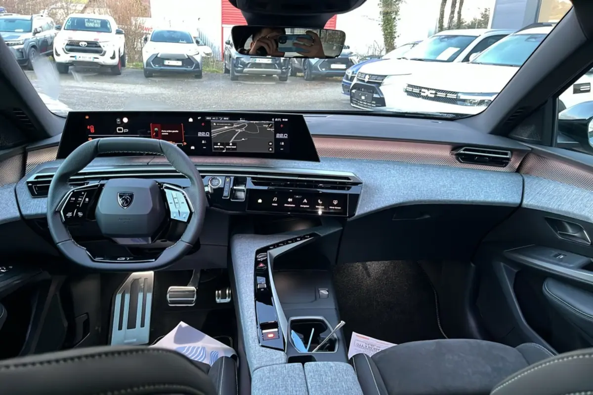 Vue intérieure avant du Peugeot 5008 Hybrid 145 GT Alcantara 2025, tableau de bord moderne avec écran large et volant cuir multifonctions.