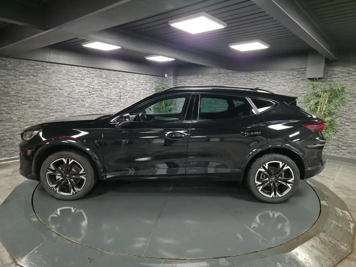 Profil côté gauche du CUPRA Formentor noir avec jantes alliage 18'' usinées dans un showroom intérieur.