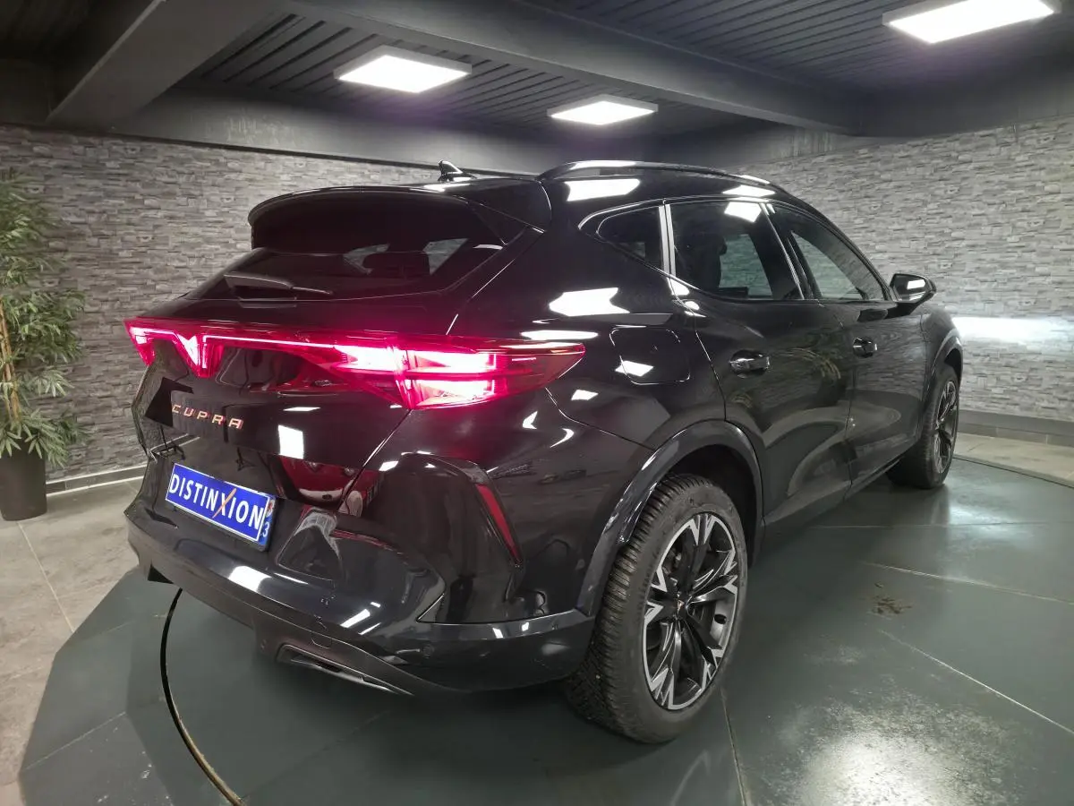 Vue 3/4 arrière droite du CUPRA Formentor noir avec feux arrière Tri-LED allumés et jantes alliage 18 pouces.