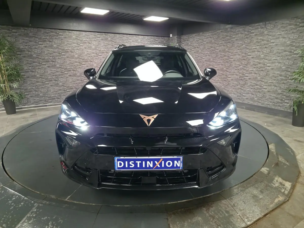 Vue frontale d'un CUPRA Formentor noir avec phares allumés et logo CUPRA cuivré sur calandre.