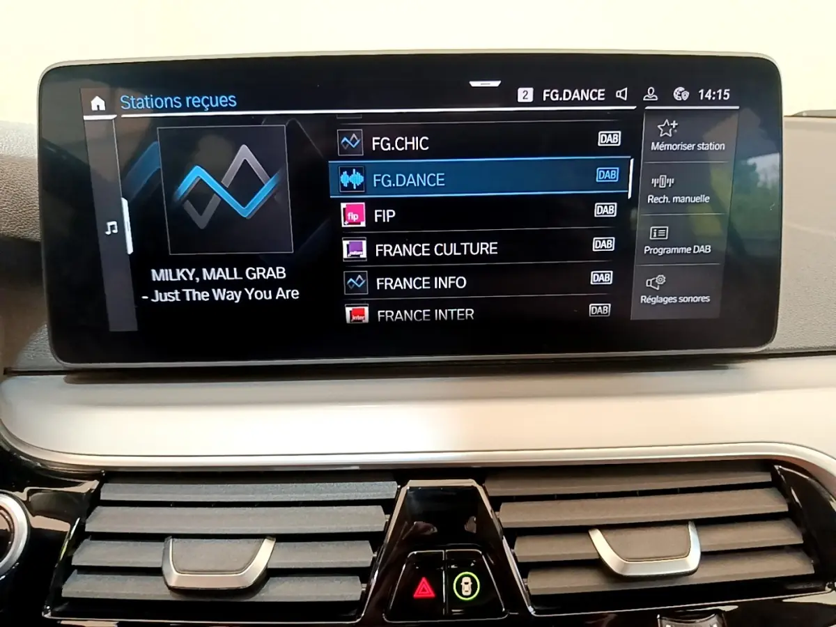 Écran tactile central affichant les stations radio dans l’habitacle d’une BMW Série 5 Touring gris clair, vue de face.