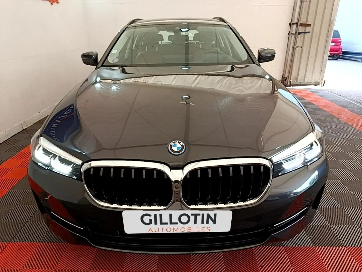 Vue frontale d'une BMW Série 5 Touring 530e gris clair avec calandre chromée et phares LED allumés.