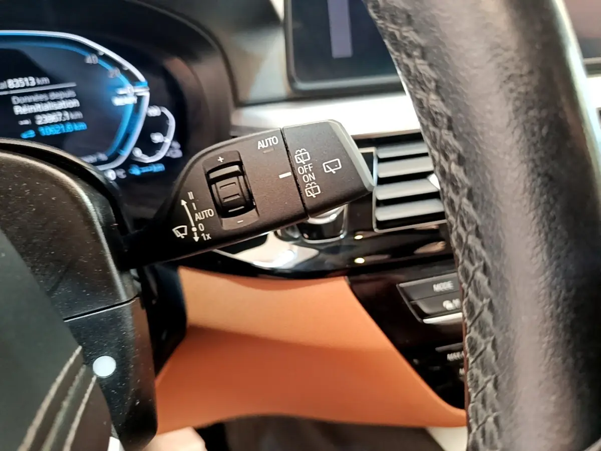 Gros plan sur la commande d’essuie-glace à gauche du volant cuir dans l’habitacle beige d’une BMW Série 5 Touring 530e.