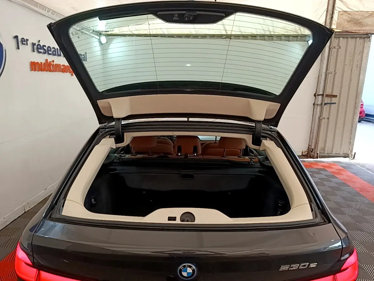 Vue arrière d’une BMW Série 5 Touring 530e gris clair avec coffre ouvert et intérieur visible en beige.