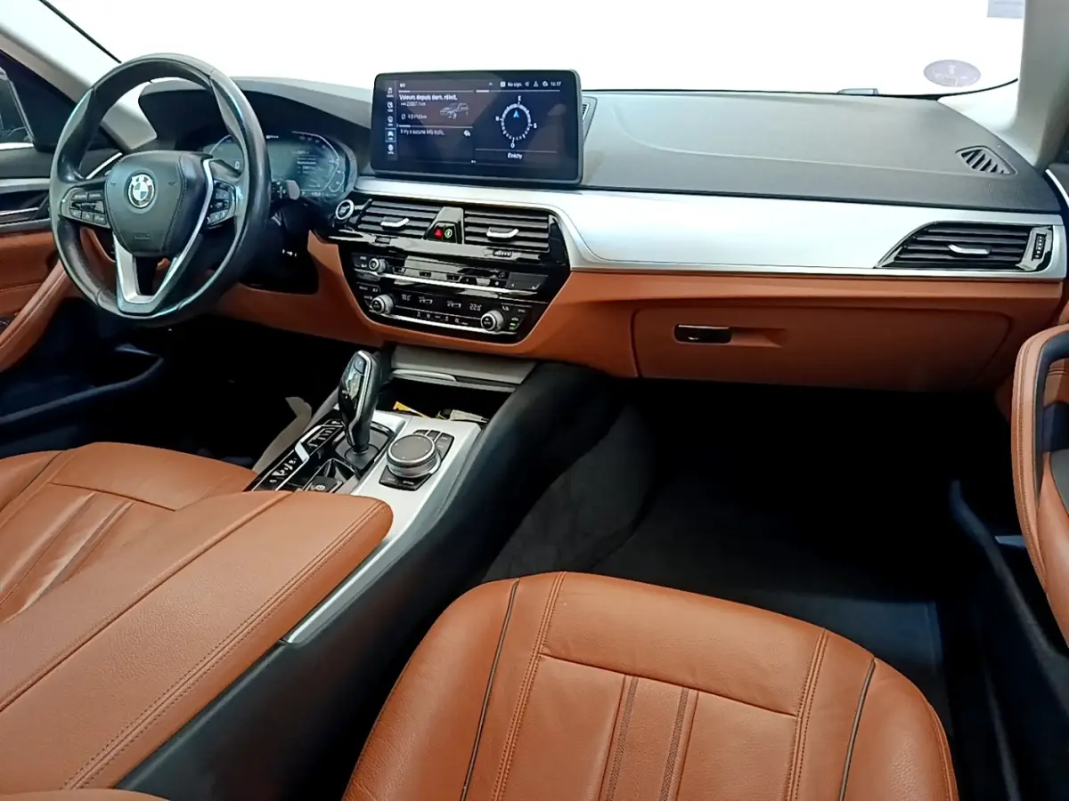 Intérieur BMW Série 5 Touring 530e 2022, vue cockpit côté conducteur, cuir marron et tableau de bord moderne gris clair.