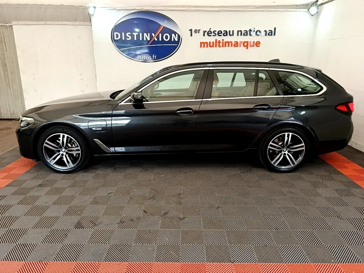 BMW Série 5 Touring 530e gris clair vue de profil côté gauche, avec jantes alliage et toit ouvrant visible.