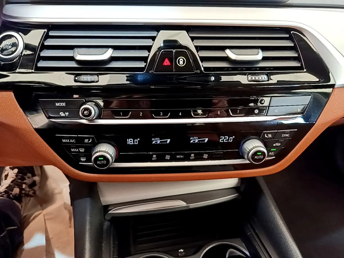 Vue rapprochée du tableau de bord noir et brun de la BMW Série 5 Touring 530e avec commandes climatisation digitales.