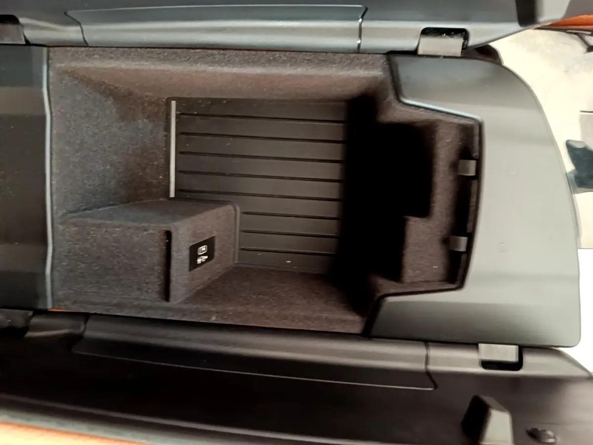 Vue intérieure en plongée du compartiment de rangement central noir d'une BMW Série 5 Touring 530e gris clair de 2022.