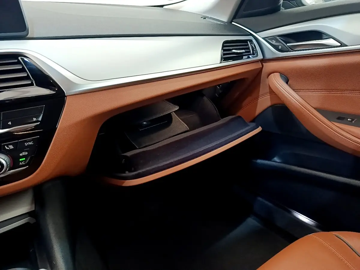 Intérieur avant droit de BMW Série 5 Touring 530e 2022 avec tableau de bord beige et garnitures cuir marron ouvert.