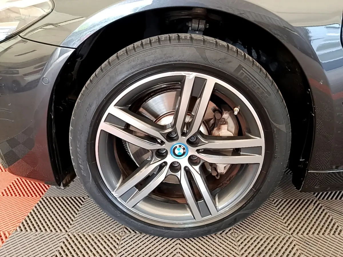 Gros plan sur la roue avant droite gris clair d'une BMW Série 5 Touring 530e avec jante alliage et logo BMW central.