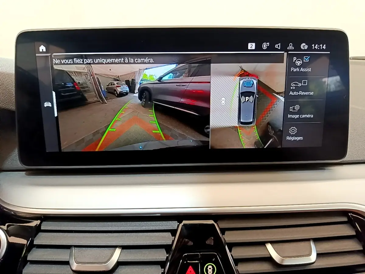 Écran tactile intérieur montrant l'aide au stationnement avec vue caméra 360° dans une BMW Série 5 Touring gris clair.