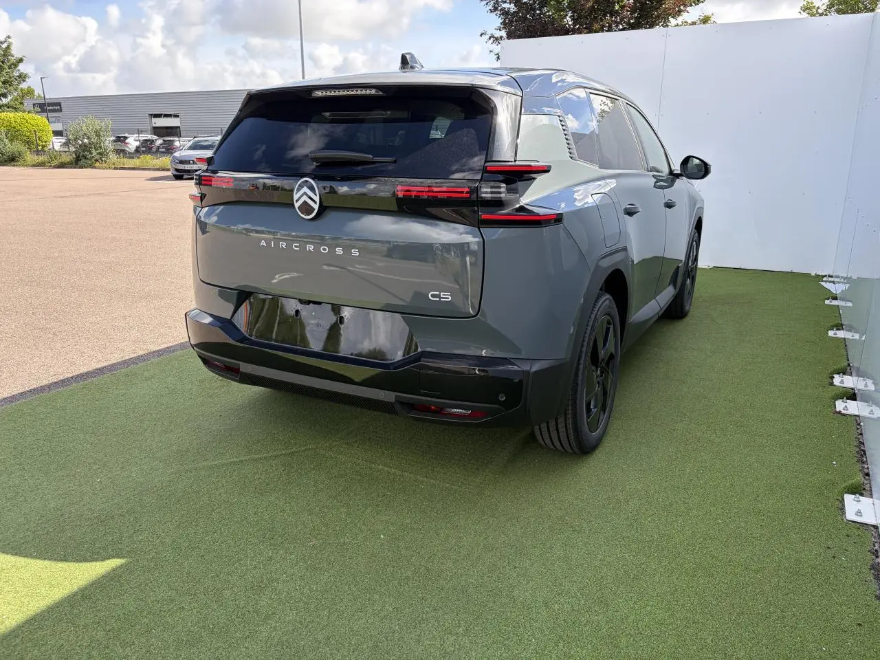 Vue 3/4 arrière droite d'un Citroën C5 Aircross vert Astoria avec toit noir et feux arrière LED distinctifs.