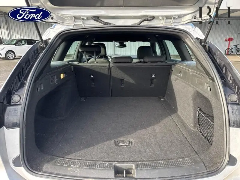 Vue arrière ouverte du coffre spacieux d'une Opel Insignia Sports Tourer gris minéral métallisé, intérieur noir avec filet latéral.