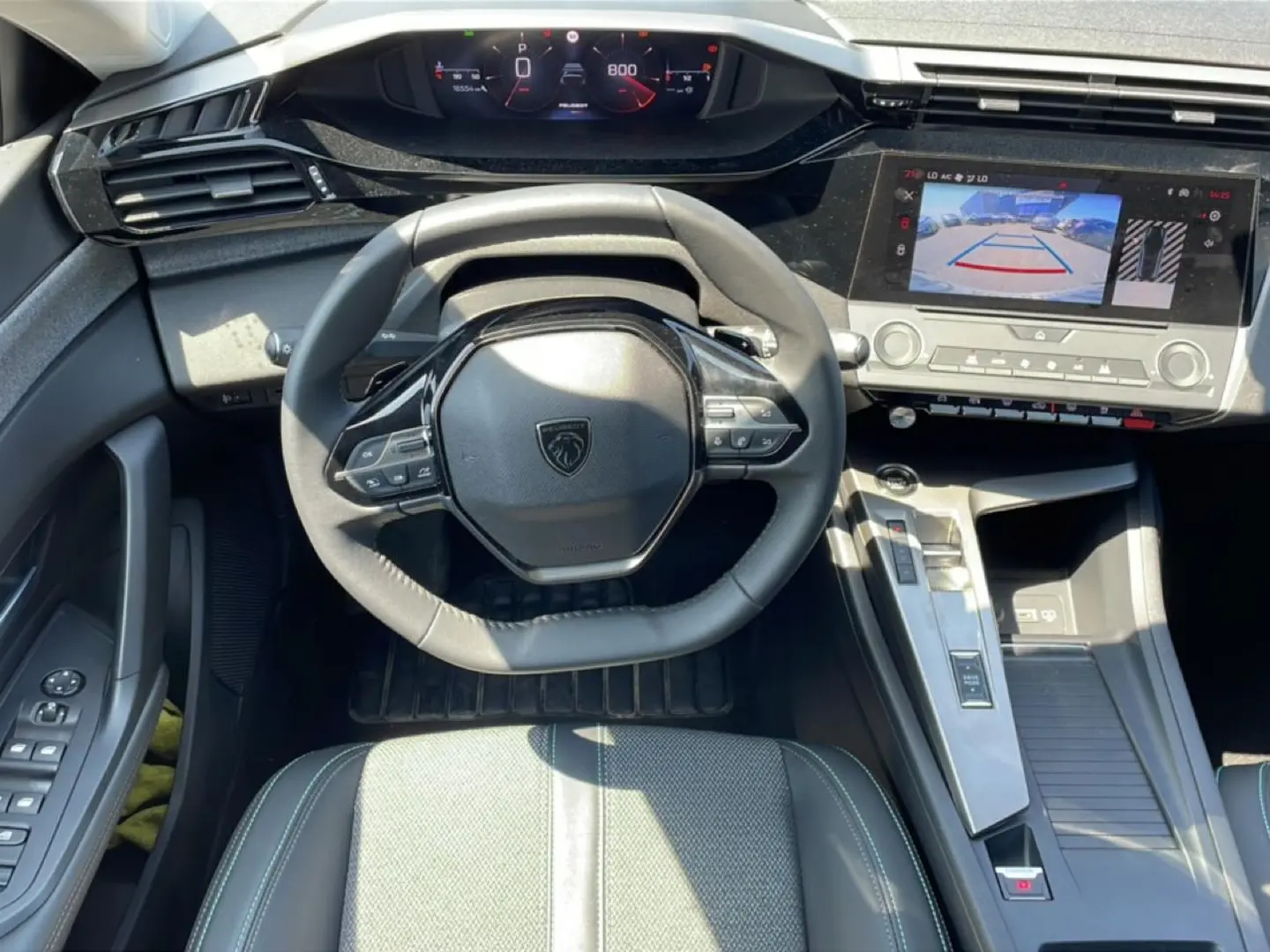 Vue intérieure frontale du poste de conduite gris du Peugeot 308 1.5 BlueHDi avec écran tactile affichant la caméra de recul.