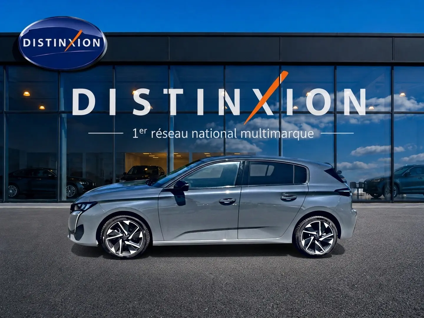 Profil droit d'une Peugeot 308 gris métallisé 2025 avec jantes alliage modernes, devant une vitrine Distinxion.