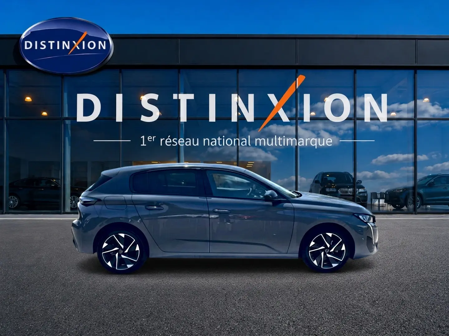Profil droit de la Peugeot 308 gris 2025 avec jantes alu noires et design moderne devant une vitrine Distinxion.