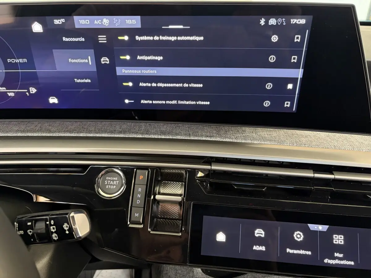 Gros plan sur le tableau de bord du Peugeot 5008 Hybrid 2025 avec écran tactile et commandes de boîte auto.