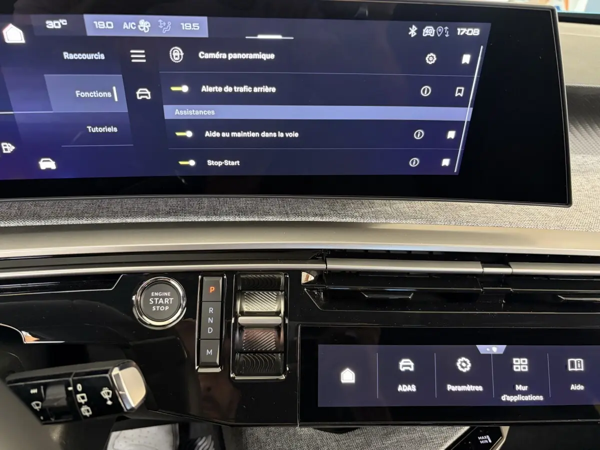 Vue rapprochée du tableau de bord du Peugeot 5008 hybride 2025, écran tactile et commande de démarrage visibles.