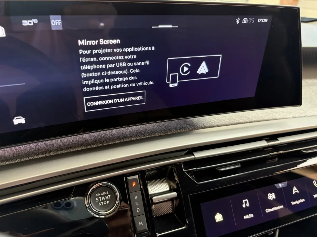 Vue rapprochée de l’écran tactile central et de la commande de démarrage du Peugeot 5008 hybride vert, intérieur moderne et épuré.