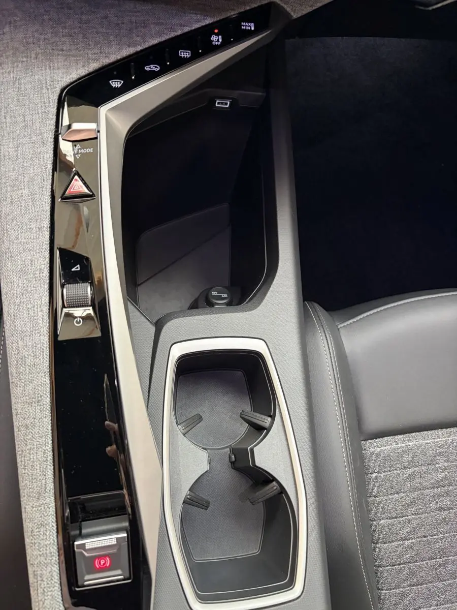 Gros plan sur la console centrale noire et grise du Peugeot 5008 Hybrid avec porte-gobelets et commandes tactiles.