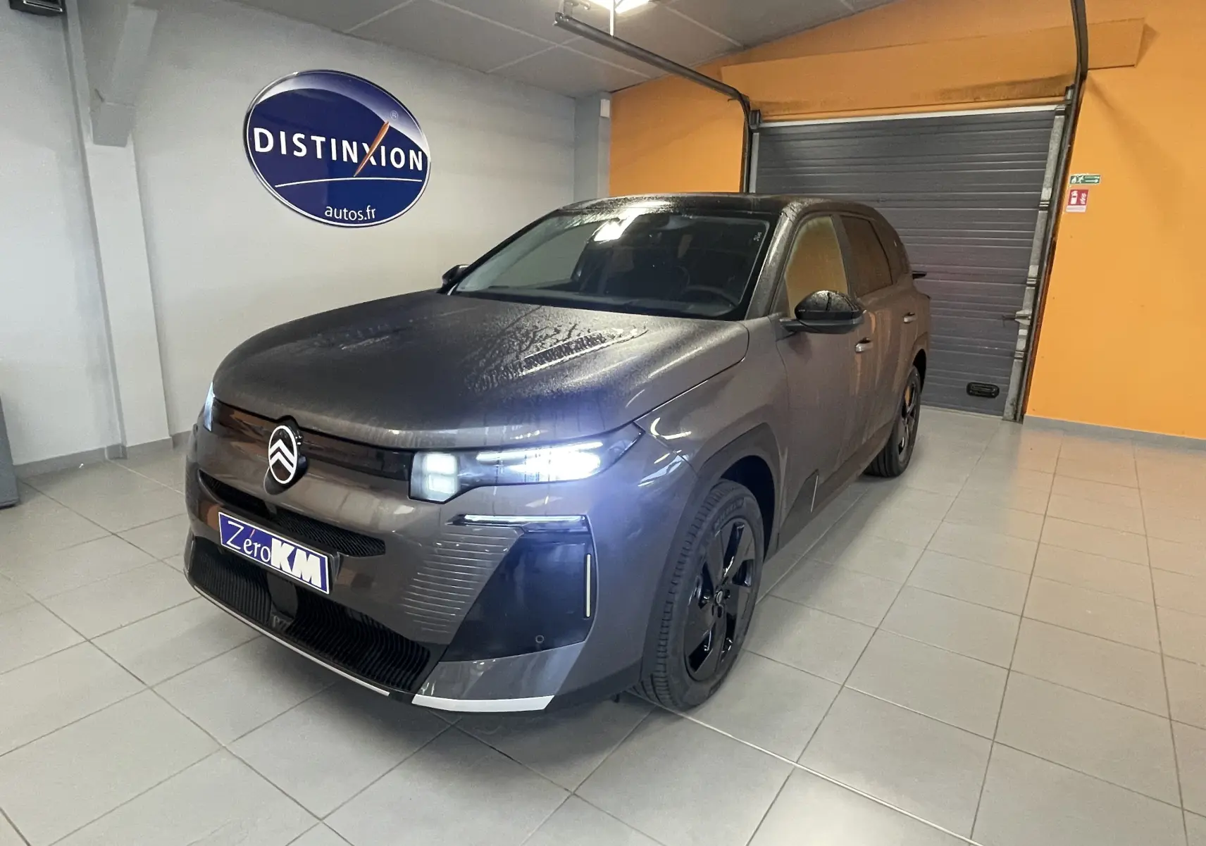 Citroën C5 Aircross hybride gris platinium en 3/4 avant droit avec toit noir et phares allumés en intérieur.