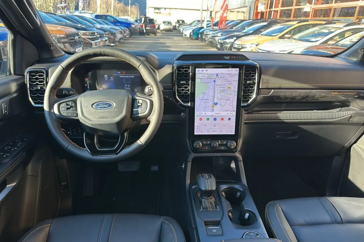 Vue intérieure avant du Ford Ranger gris carbone 2026, avec volant cuir multifonctions et écran tactile central vertical.