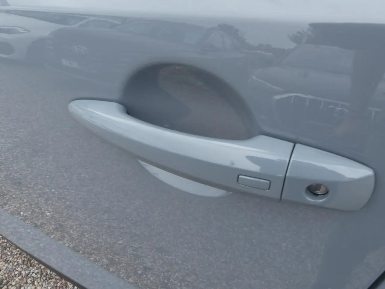 Poignée de porte côté gauche gris métallisé du Nissan Qashqai 1.5 e-Power 2025 avec serrure et bouton d'ouverture.