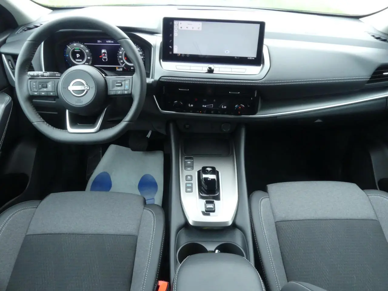 Intérieur du Nissan Qashqai 2025, vue avant centrée sur tableau de bord, console et sièges gris tissu et TEP.