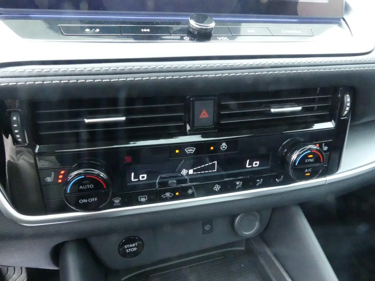 Détail de la console centrale noire brillante du Nissan Qashqai 1.5 e-Power 2025 avec commandes climatisation et bouton Start/Stop.
