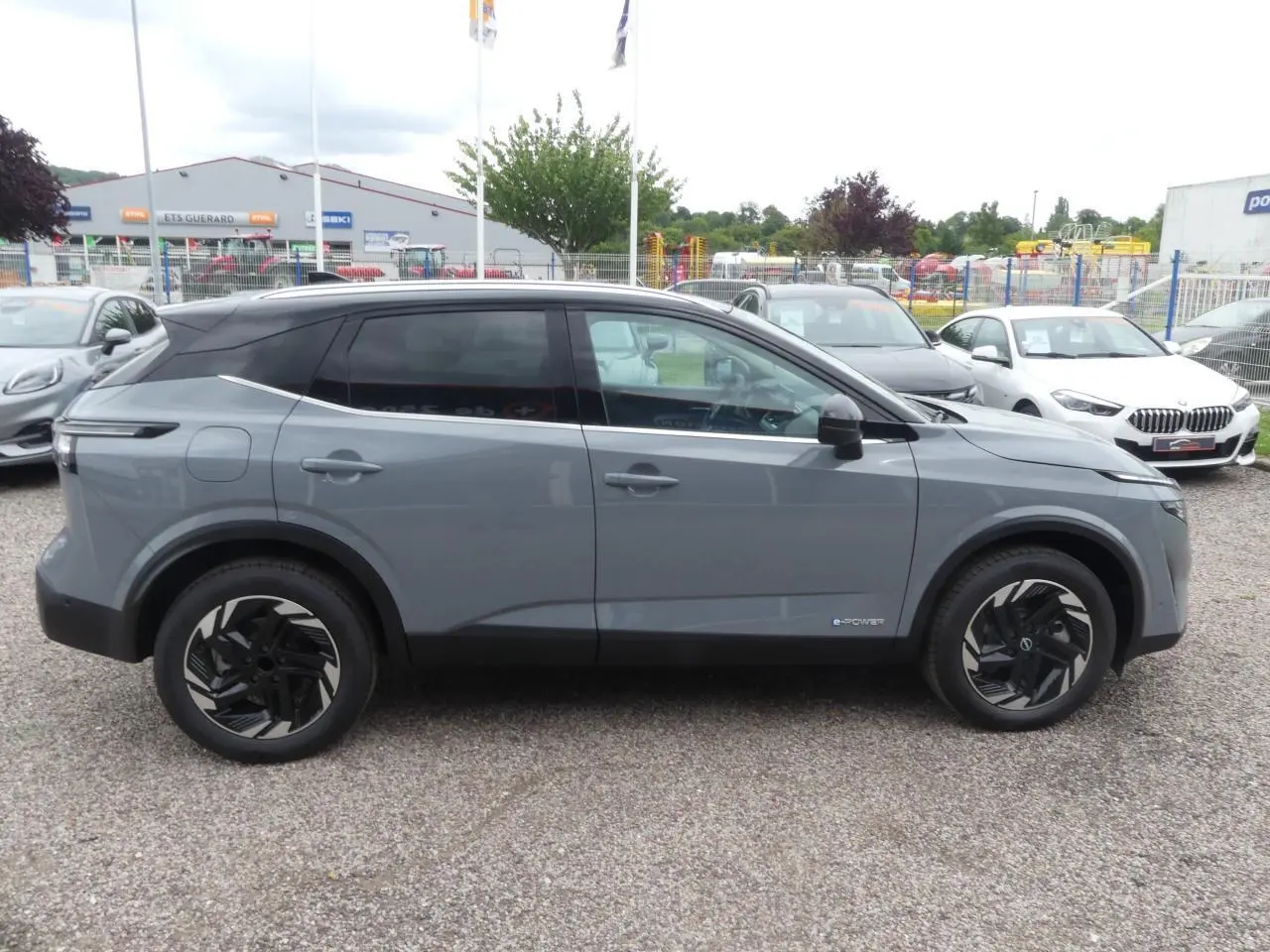 Nissan Qashqai 1.5 e-Power gris métallisé vu de profil côté gauche avec toit noir et jantes alliage noires.