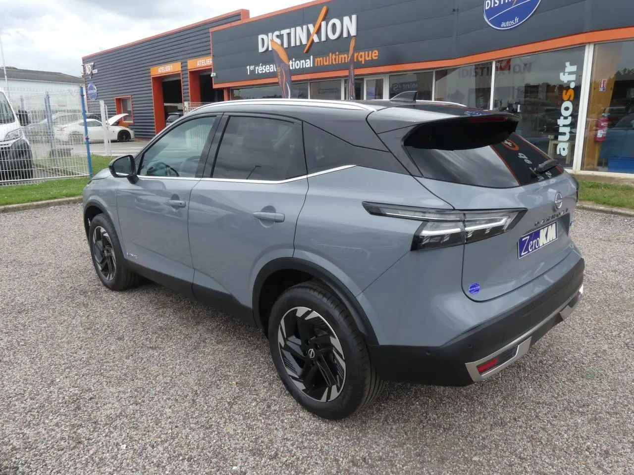 Nissan Qashqai 2025 gris métallisé bi-ton, vue 3/4 arrière côté gauche avec toit noir panoramique.