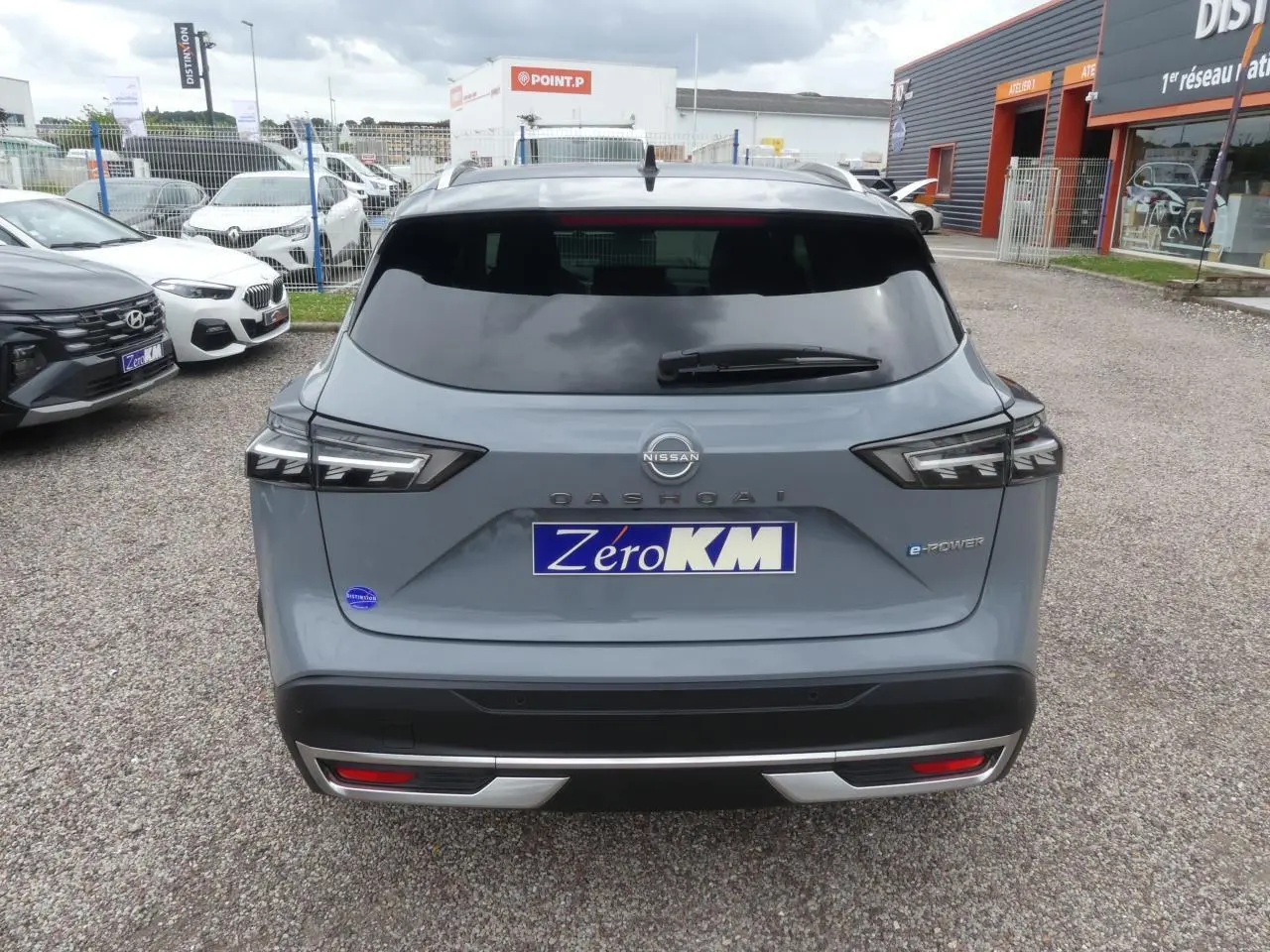Vue arrière d'un Nissan Qashqai gris métallisé avec feux LED et badge e-Power sur un parking extérieur.