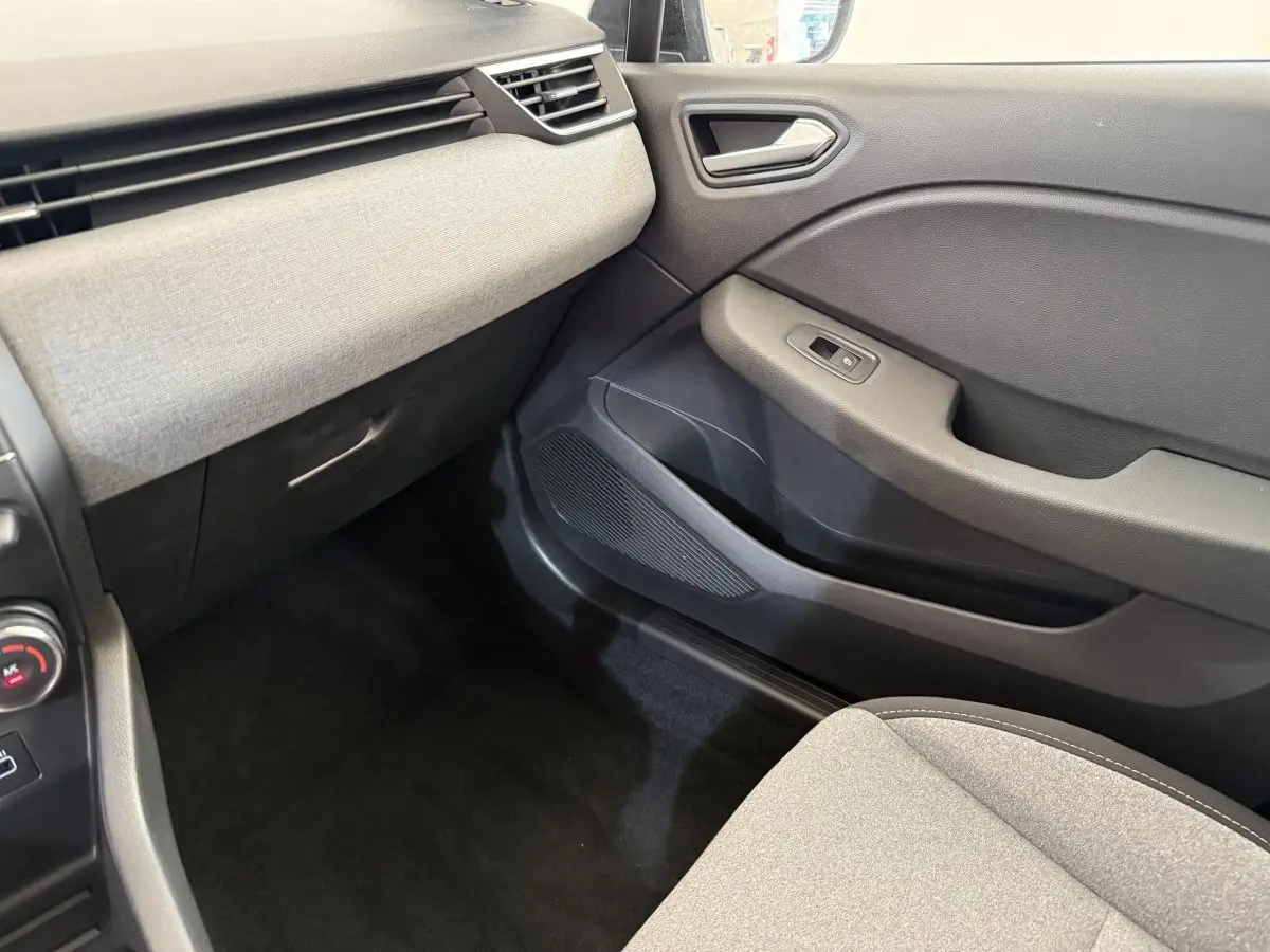 Intérieur côté passager de la Renault Clio noir 2025, montrant la porte et la partie inférieure du tableau de bord gris clair.