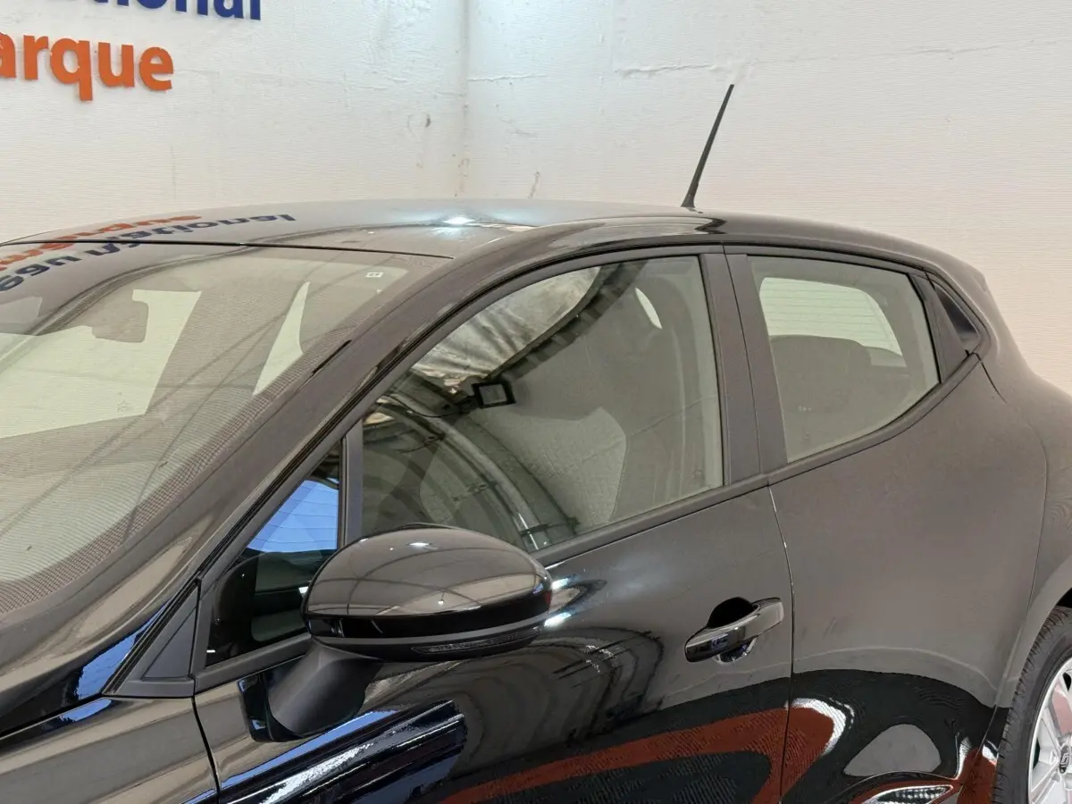 Profil côté gauche de la Renault Clio noire 2025 avec rétroviseur ton caisse et poignée de porte visible.