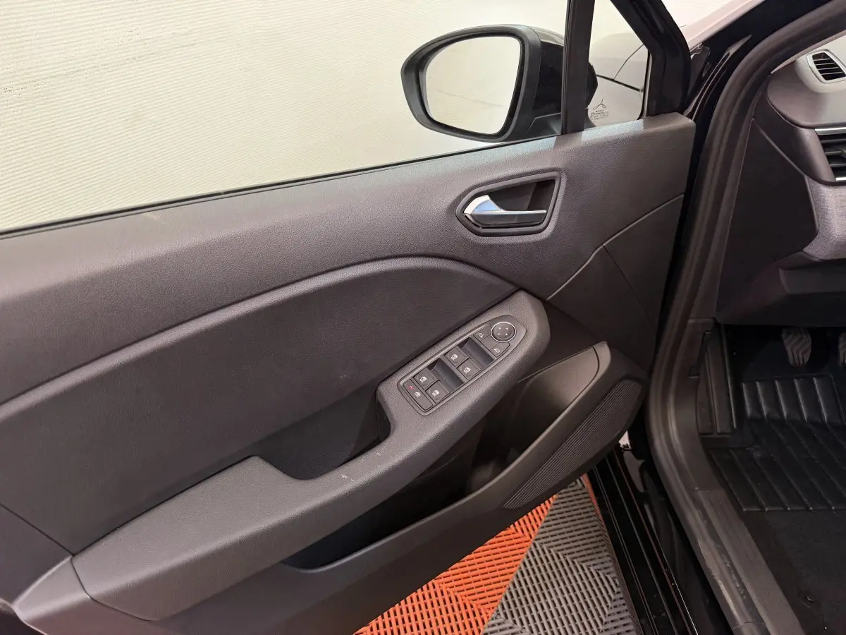 Vue intérieure côté gauche de la porte avant noire d'une Renault Clio 2025 avec commandes électriques des vitres.