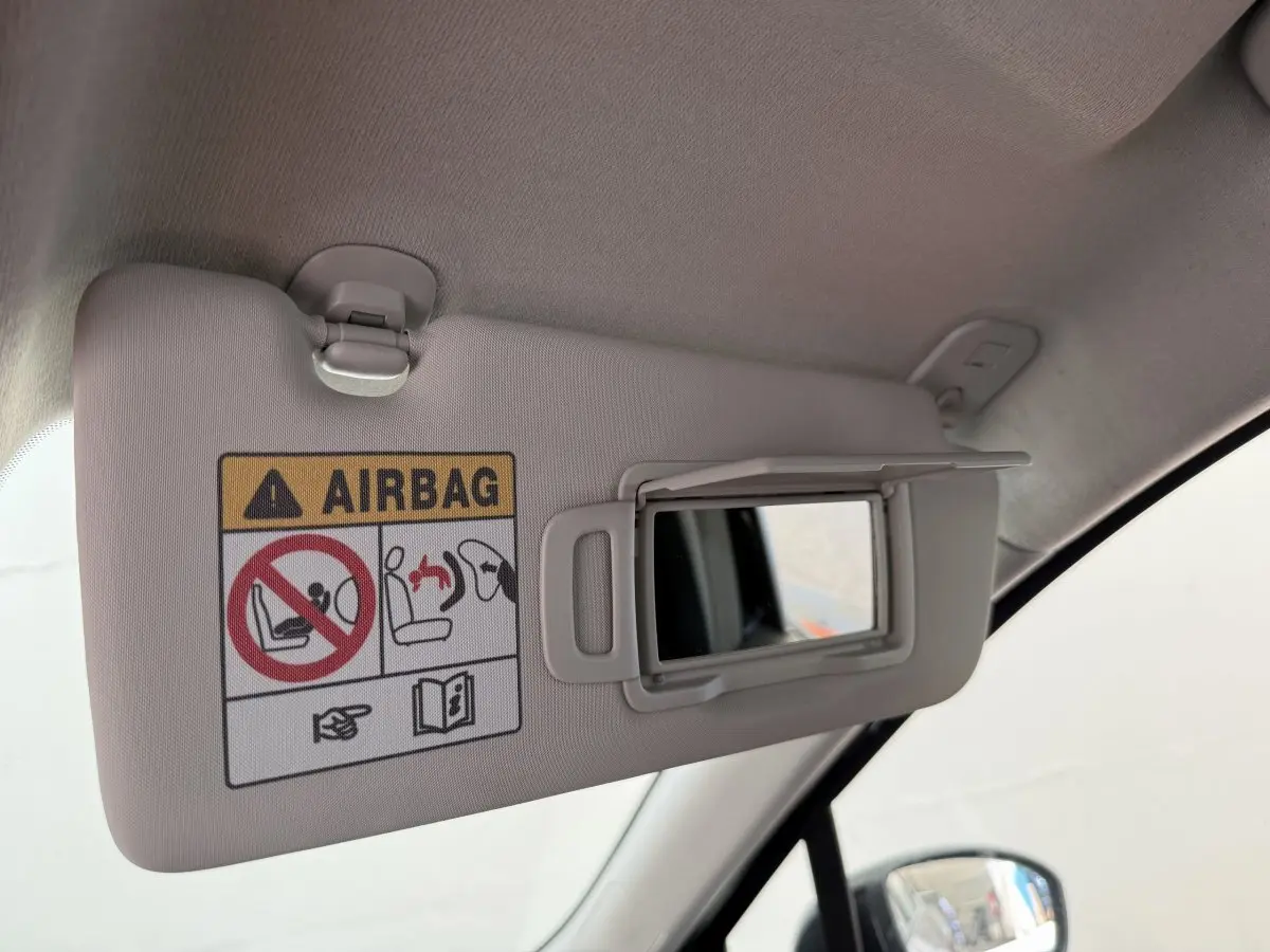 Détail du pare-soleil côté conducteur beige avec miroir ouvert et avertissement airbag dans une Renault Clio noire 2025.