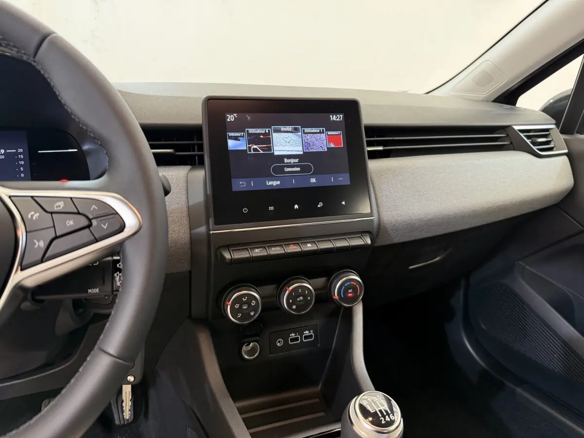 Vue intérieure côté conducteur de la Renault Clio noire 2025, tableau de bord avec écran tactile et volant multifonctions cuir.