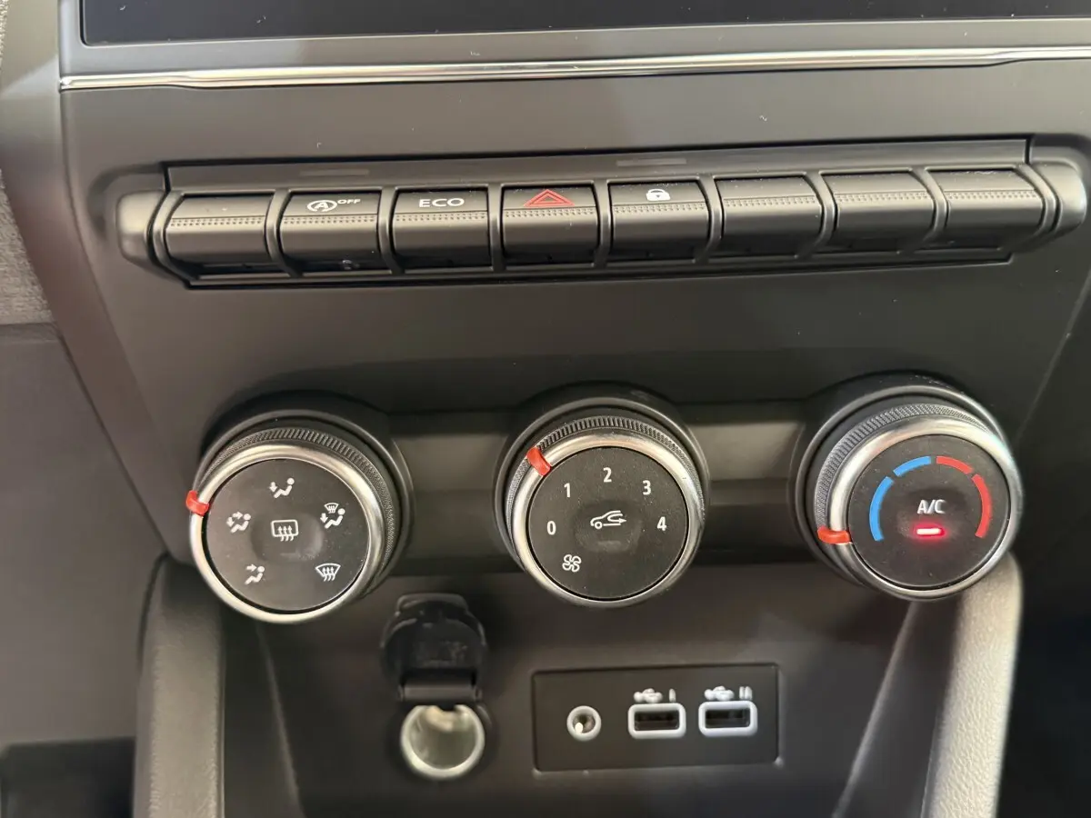 Gros plan sur les commandes de climatisation et les ports USB du tableau de bord de la Renault Clio noire Evolution 2025.