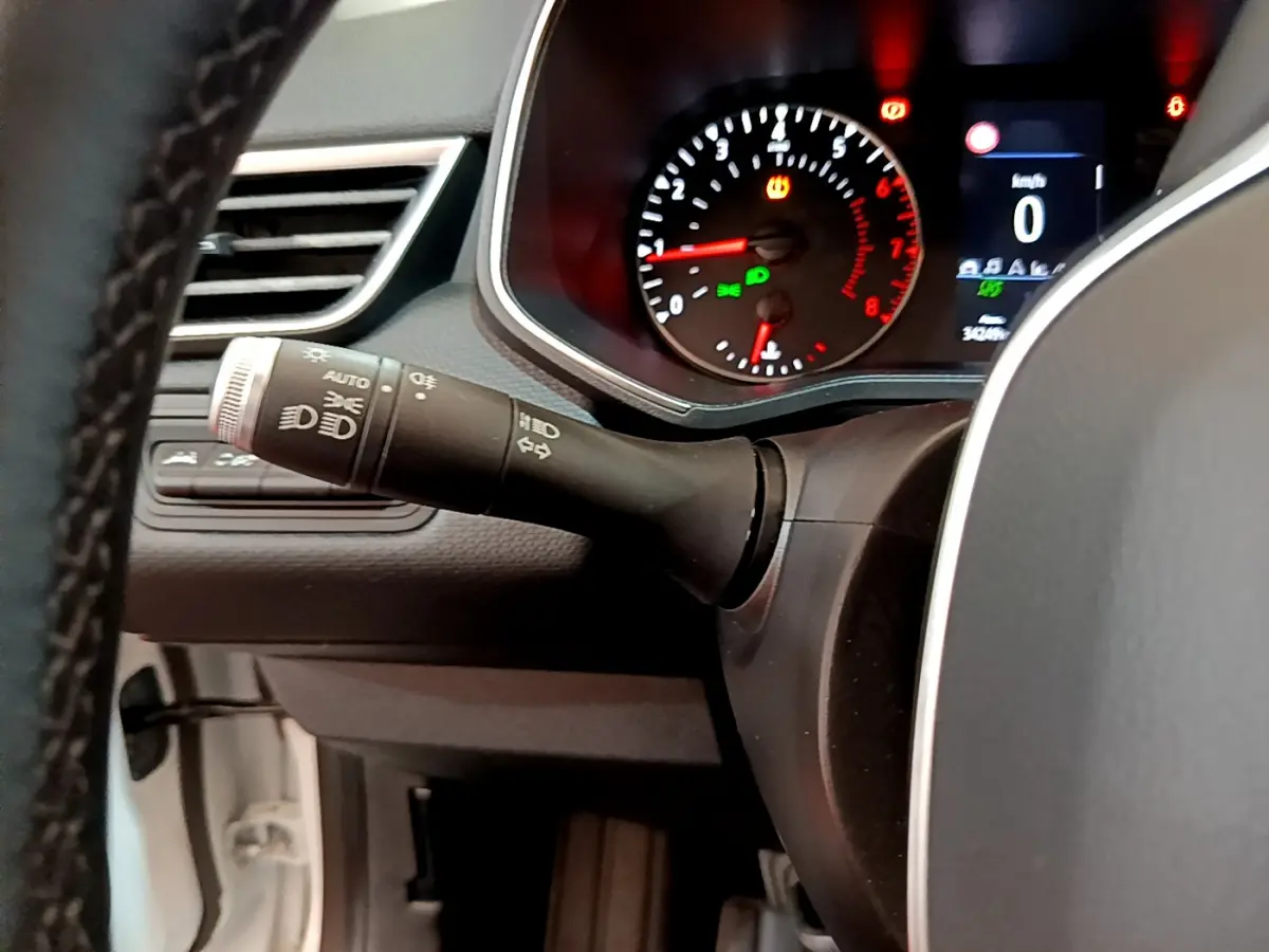 Gros plan sur le commodo gauche et le tableau de bord éclairé de la Renault Clio Business TCe 100 blanche de 2020.