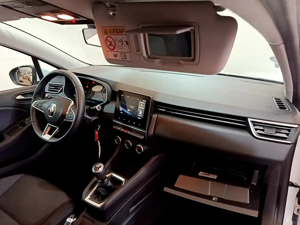 Vue intérieure côté conducteur de la Renault Clio Business TCe 100 2020 blanche, volant cuir et écran tactile central allumé.