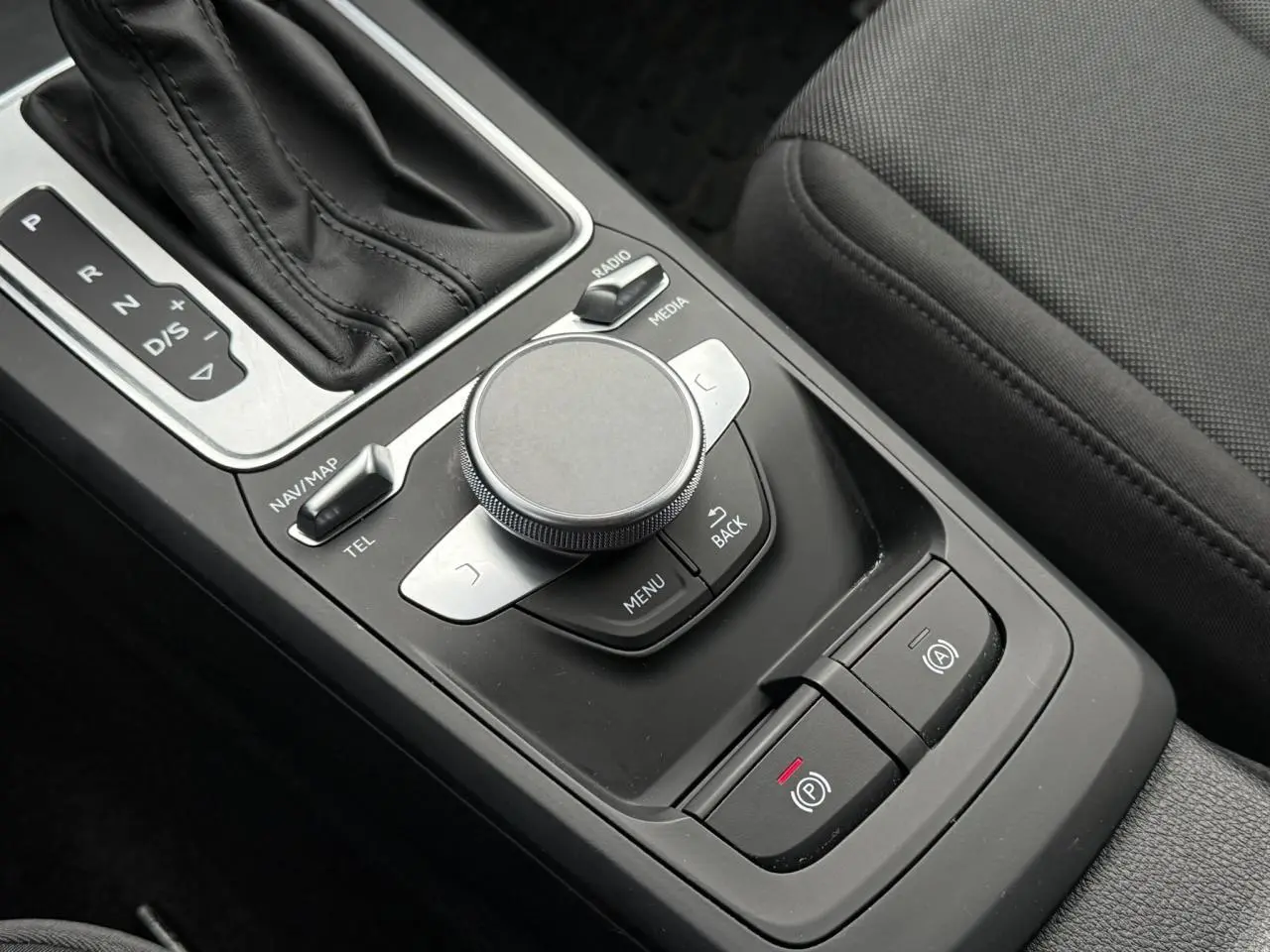 Gros plan sur la console centrale noire de l'Audi Q2 35 TFSI 2023 avec molette de contrôle et levier de boîte automatique.