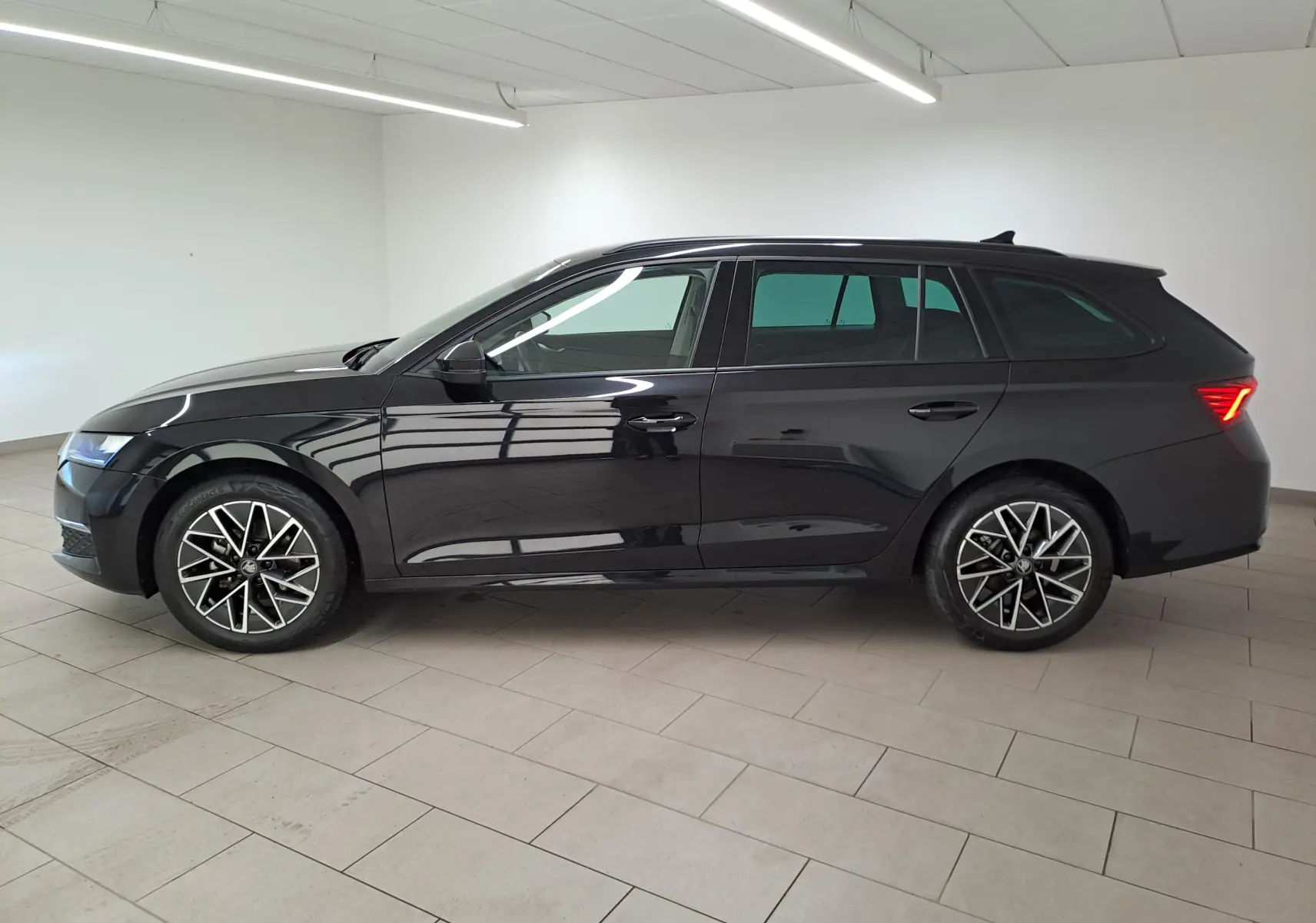 Profil droit d'une Skoda Octavia Combi 2025 noire Magic nacré avec jantes alliage 17'' Slagard Aero noir polies et vitres surteintées.