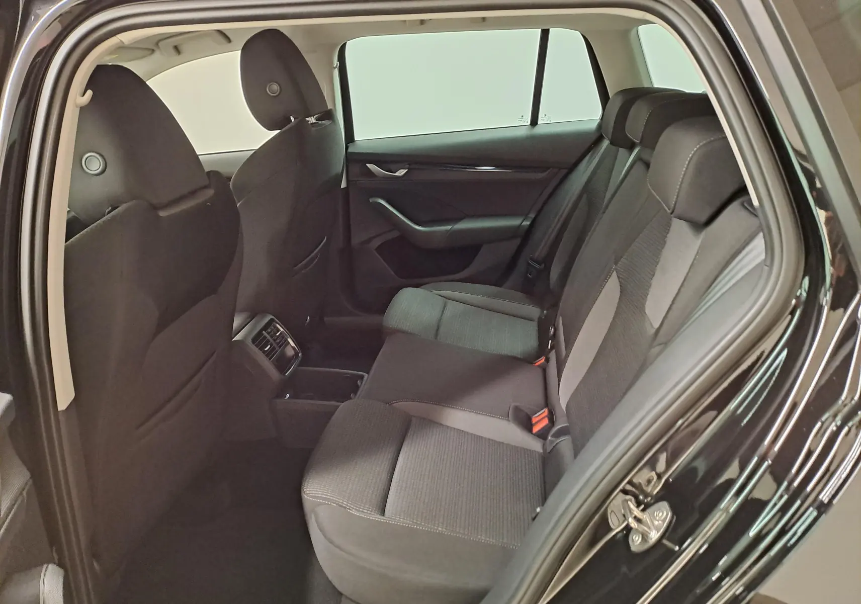 Vue intérieure côté droit des sièges arrière noirs d'une Skoda Octavia Combi 2025 avec portière ouverte.