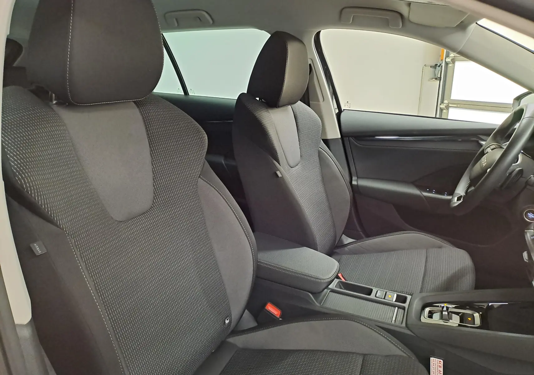 Vue intérieure côté droit des sièges avant noirs et de la console centrale d'une Skoda Octavia Combi 2025.