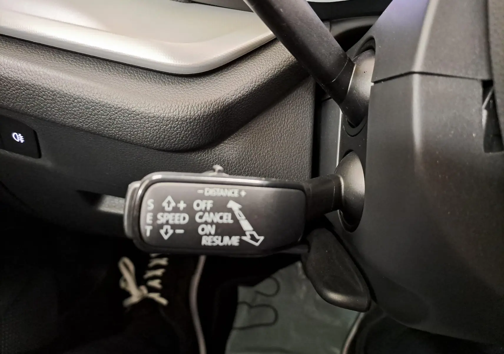 Gros plan sur la commande de régulateur de vitesse à gauche du volant dans une Skoda Octavia Combi noire.